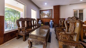 A spacious living area with a large wooden coffee table, ornate wooden sofas, and a painting on the wall. - Phong Lan 2 Hotel (Ho Chi Minh City)