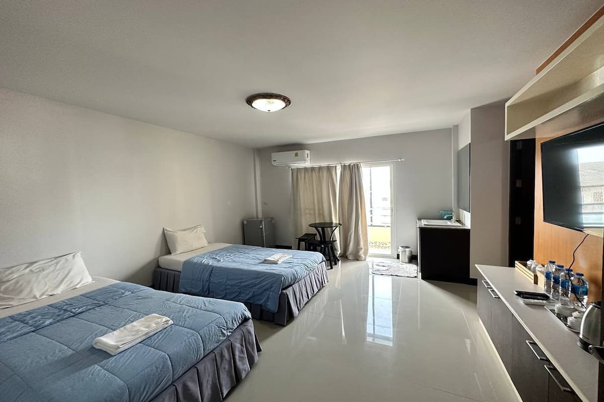 Une chambre d’hôtel avec deux lits, une petite table, un téléviseur et une kitchenette.