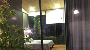 A bedroom with a bed, a window, and a view of the outside.