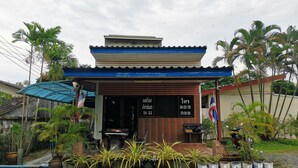 Ein kleines Gebäude mit blauem Dach und einem Schild mit thailändischen Schriftzeichen.