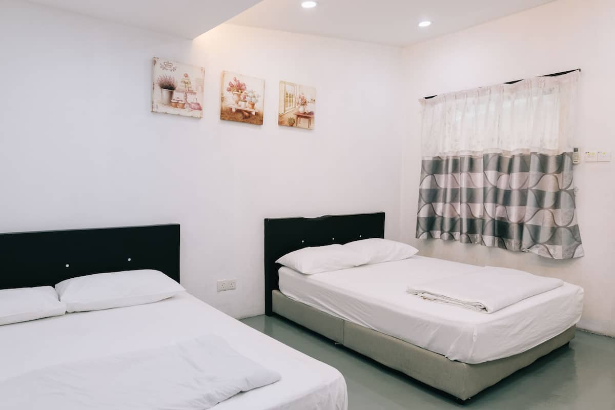A room with two beds, a window with a curtain, and three wall-mounted pictures.