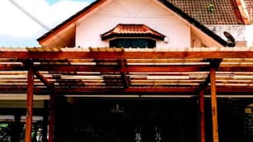 Une maison traditionnelle avec un toit en tuiles, une véranda et une antenne parabolique bien visible.