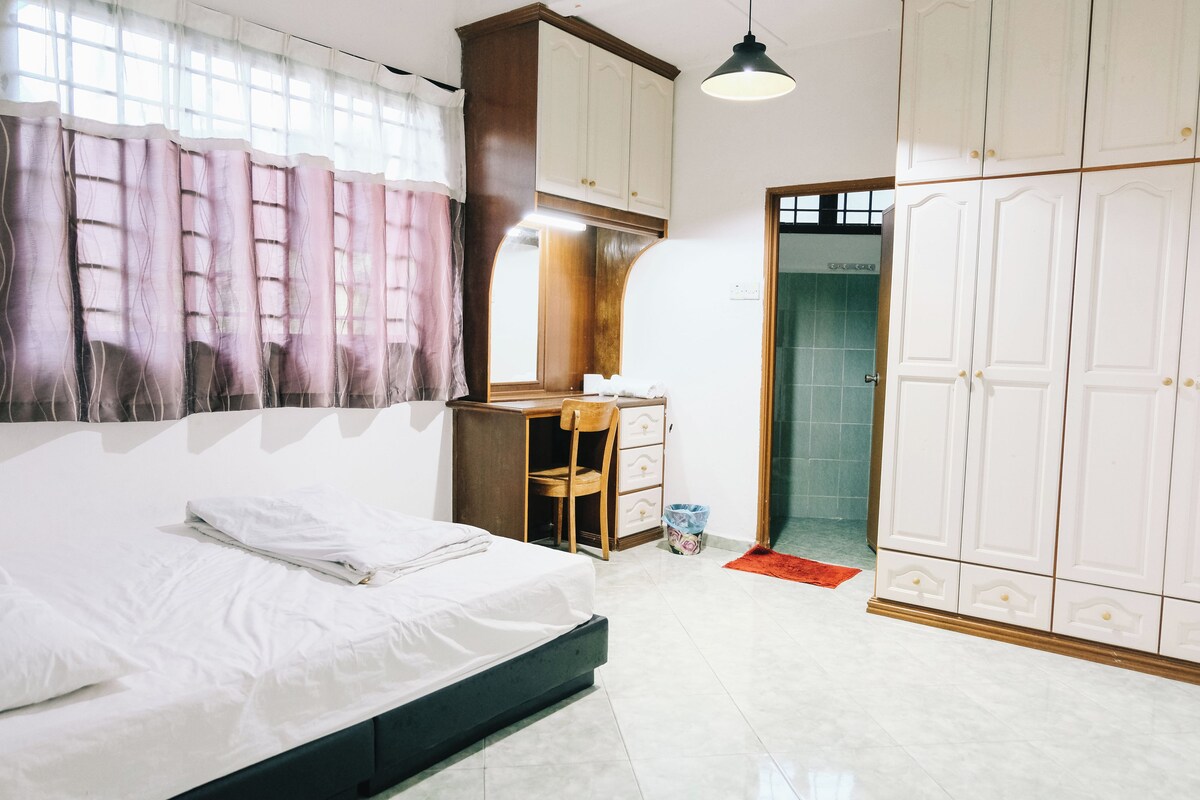 A bedroom with a bed, a desk, and a wardrobe.