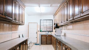 Une cuisine étroite avec des meubles en bois, un pare-feu en carrelage et une petite fenêtre.