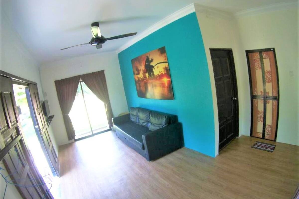 A room with a ceiling fan, a sofa, a painting, and a door.