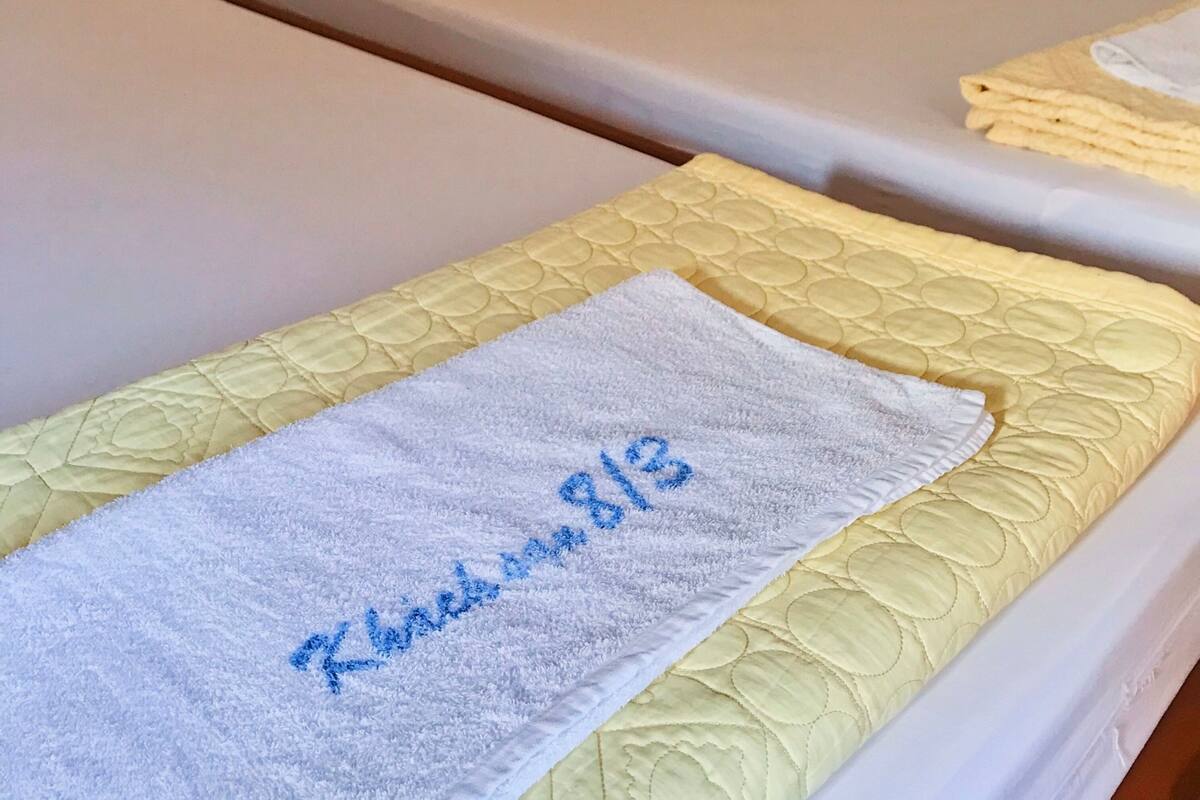 Une chambre d’hôtel avec deux lits simples, chacun étant équipé d’un oreiller et d’une serviette soigneusement pliée.