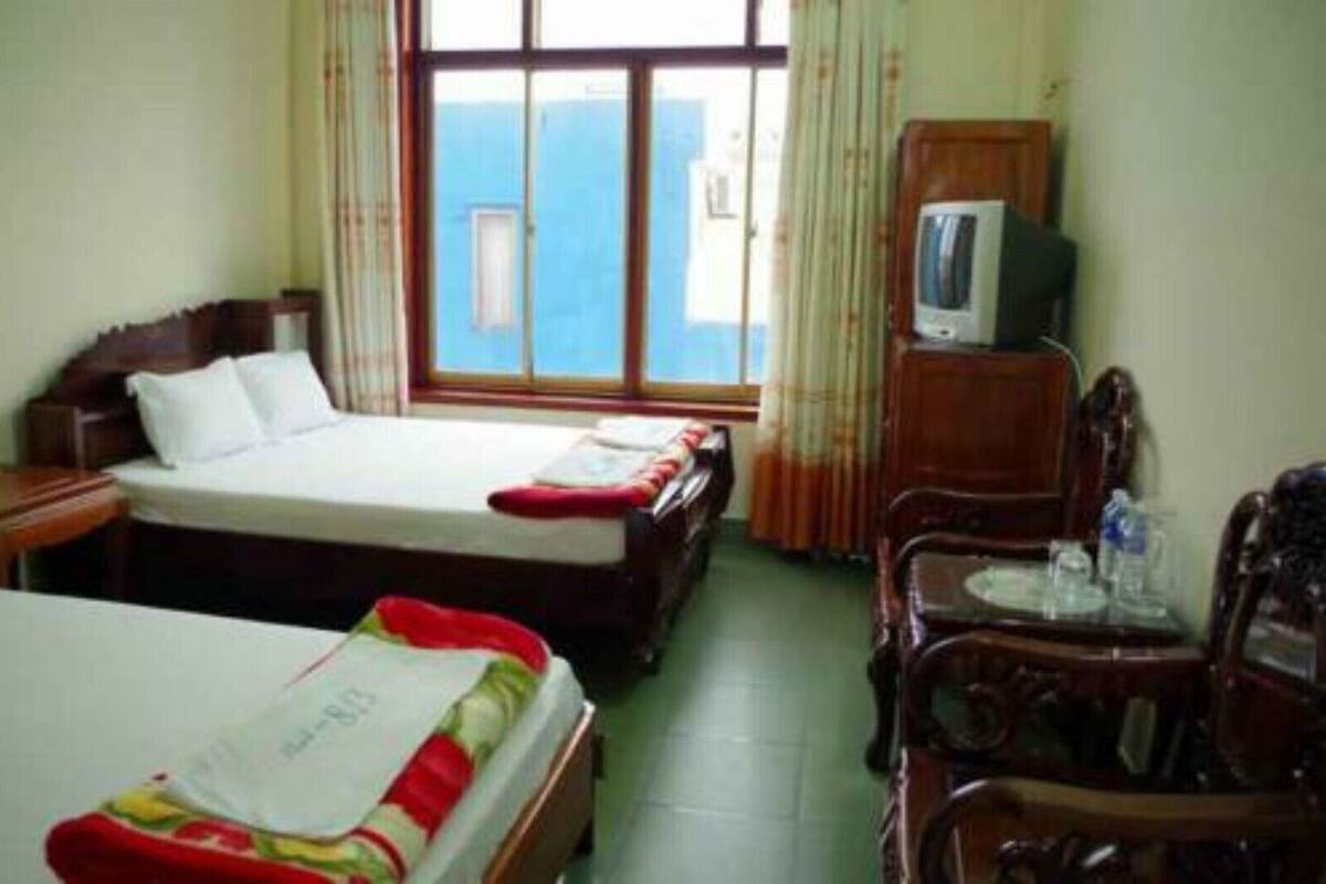 Une chambre d’hôtel avec deux lits, une télévision, un bureau et une chaise.