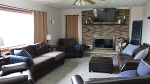 A living room with a fireplace, leather sofas, and a flat-screen TV mounted above it. - Peaceful, Family-Friendly Ridge-Top Retreat with Southern Views (Rome)