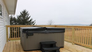 A hot tub on a wooden deck with a wooden railing, a step stool, and a view of trees and hills in the background. - Peaceful, Family-Friendly Ridge-Top Retreat with Southern Views (Rome)