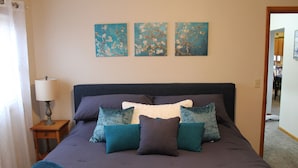 A bedroom with a bed, pillows, a nightstand, a lamp, and three wall-mounted paintings. - Peaceful, Family-Friendly Ridge-Top Retreat with Southern Views (Rome)