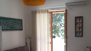 Una sala de estar con sofá, una mesa de comedor y un amplio ventanal con cortinas.