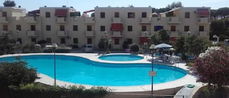 A swimming pool surrounded by a fence, with a building in the background.