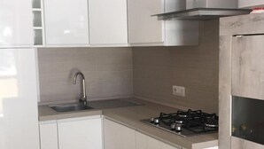 Una cocina moderna con armarios blancos, una campana de acero inoxidable y una estufa a gas empotrada.