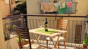 Un balcon avec une table et des chaises, des plantes en pot et du linge suspendu pour sécher.