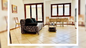 Un salon avec un canapé, une table à manger et des chaises, ainsi qu’un téléviseur.