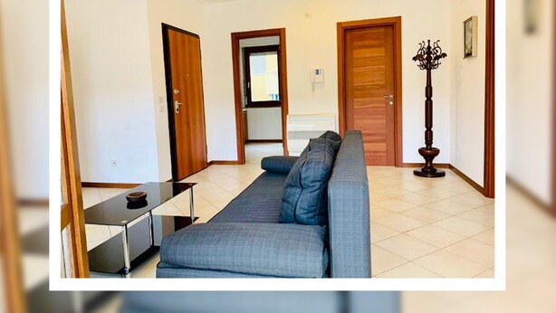 Un salon avec un canapé, une table basse et une lampe. Des portes donnent accès aux autres pièces.