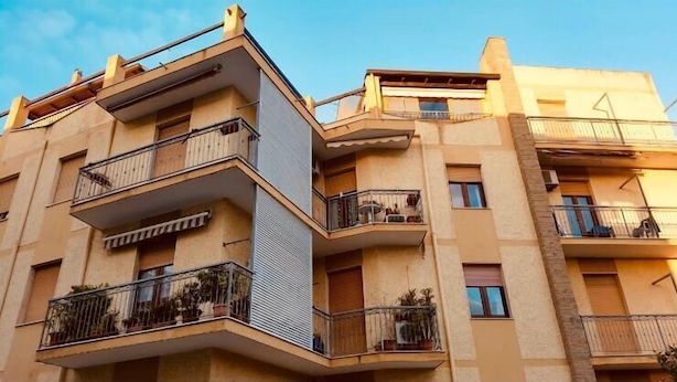 A multi-story residential building with balconies, a flat roof, and a clear sky. - Casa Granseola (Alghero)