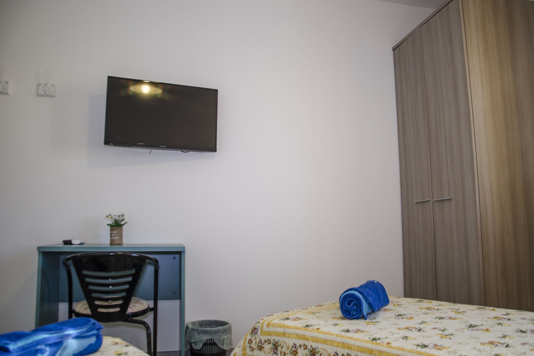 A bedroom with a bed, a desk, a chair, a television, and a wardrobe.