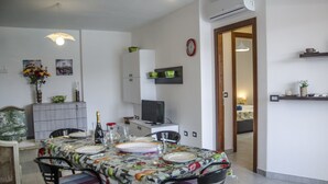 Un coin repas avec une table dressée pour quatre personnes, un téléviseur et une horloge au mur.