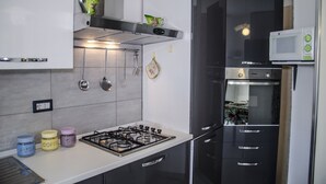 Une cuisine moderne équipée d’une cuisinière à gaz, d’un four à micro-ondes, d’un four et d’appareils électroménagers en acier inoxydable.