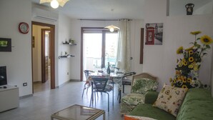Un salon avec un canapé vert, une table basse et un coin repas comprenant des chaises et une table.