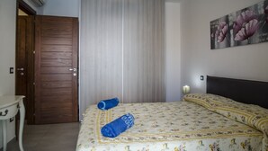 Une chambre à coucher avec un lit, une porte en bois, un mur blanc et un tableau.