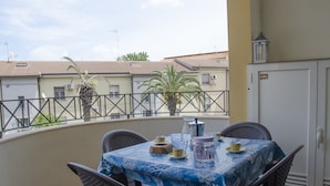 Un balcón con una mesa preparada para el té, sillas y vistas a edificios cercanos.