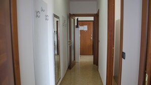 Un pasillo estrecho con puertas a ambos lados, que conduce a una habitación al final.