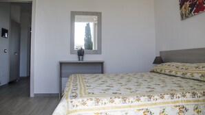 A bedroom with a bed, a bedside table, a mirror, and a potted plant. - Casa Tracina (Alghero)