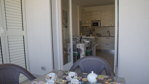 Un coin repas avec une table dressée pour quatre personnes, une chaise et une vue sur une cuisine équipée de placards et d’un four à micro-ondes.