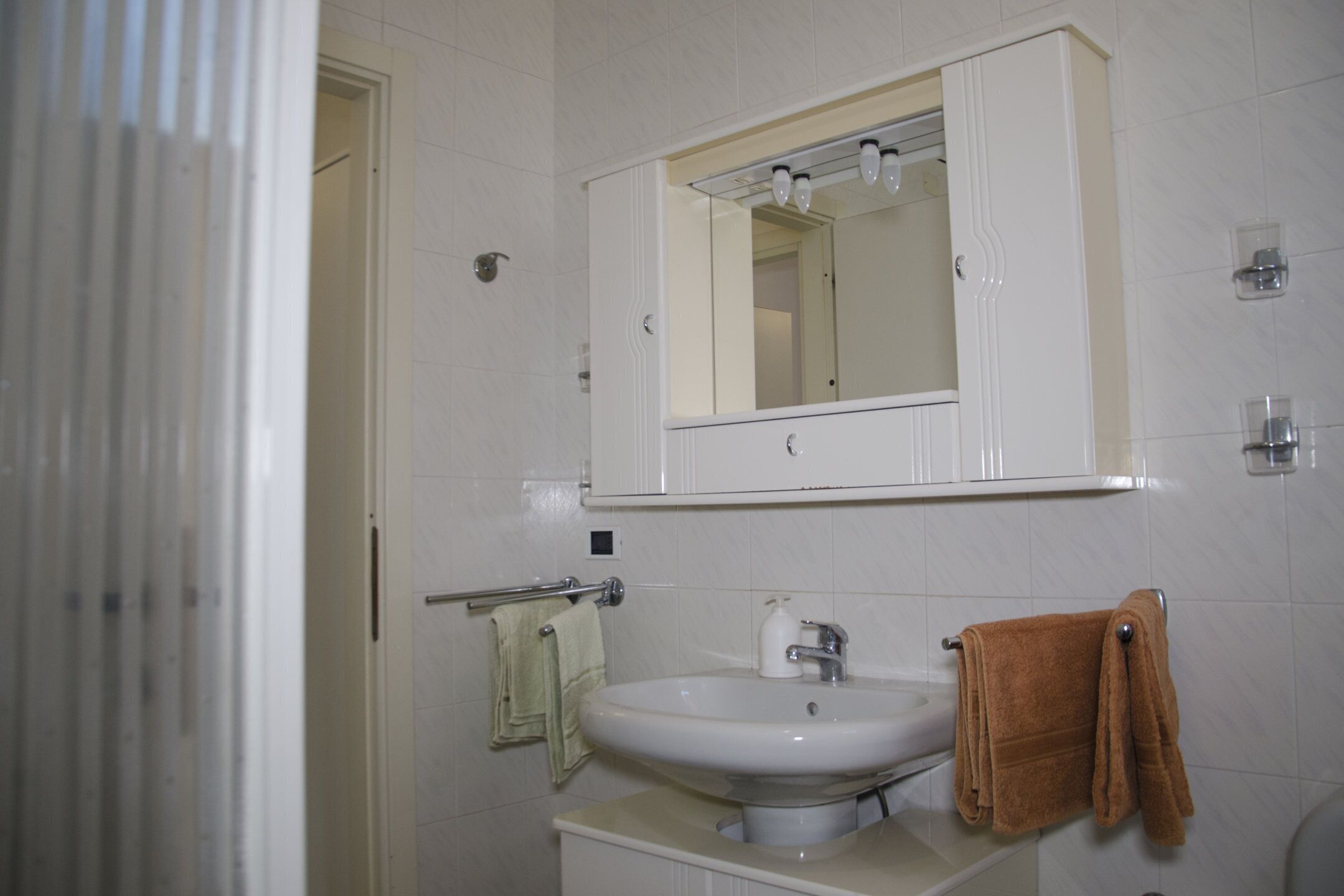 A bathroom with a white sink, mirror, and towel rack.