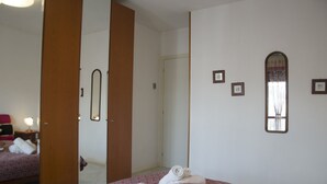 A hotel room with a bed, a mirror, and a door leading to another room. - Casa Muggine (Alghero)