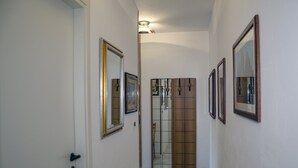 A hallway with white walls, a wooden door, and several framed mirrors. - Casa Muggine (Alghero)