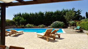 Uma área de piscina com espreguiçadeiras e um pérgula.