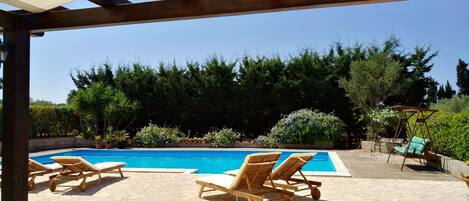 A pool area with lounge chairs and a pergola.