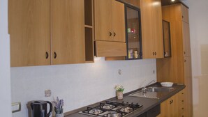 A modern kitchen with wooden cabinets, a gas stove, a sink, and a small countertop area.