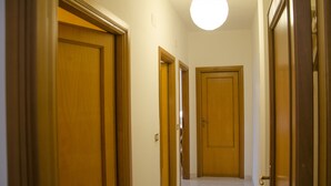 A hallway with wooden doors and a light fixture on the ceiling. - Casa Lampuga (Alghero)