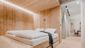 Une pièce aux lignes épurées, avec un mobilier en bois comprenant un lit, une petite table et une chaise.