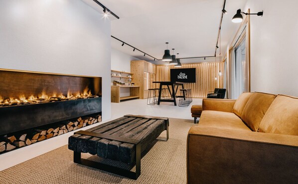 A modern living room with a fireplace, a sofa, and a TV. - das bleibt (Schladming)