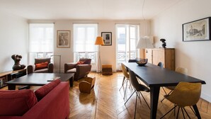 A modern living room with a sofa, armchairs, a dining table, and a lamp. - Spacious flat in Batignolles quarter (Paris)