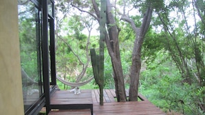 Un hamac sur une terrasse en bois, avec vue sur une forêt.
