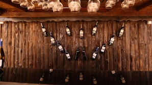 A wooden wall with bottles of wine and wine glasses hanging from the ceiling. - Epoch Stone House (Nevsehir)