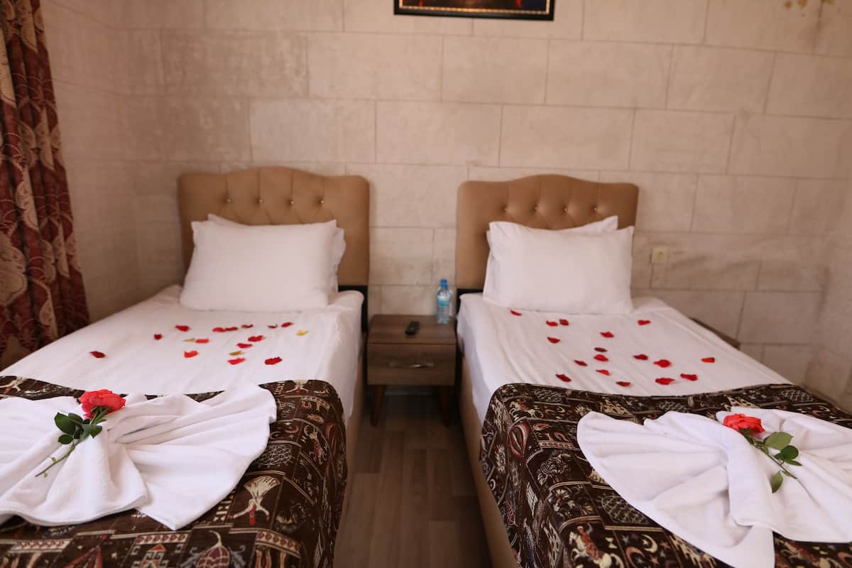 Two twin beds with headboards, a wooden nightstand between them, and a wall with a framed picture.
