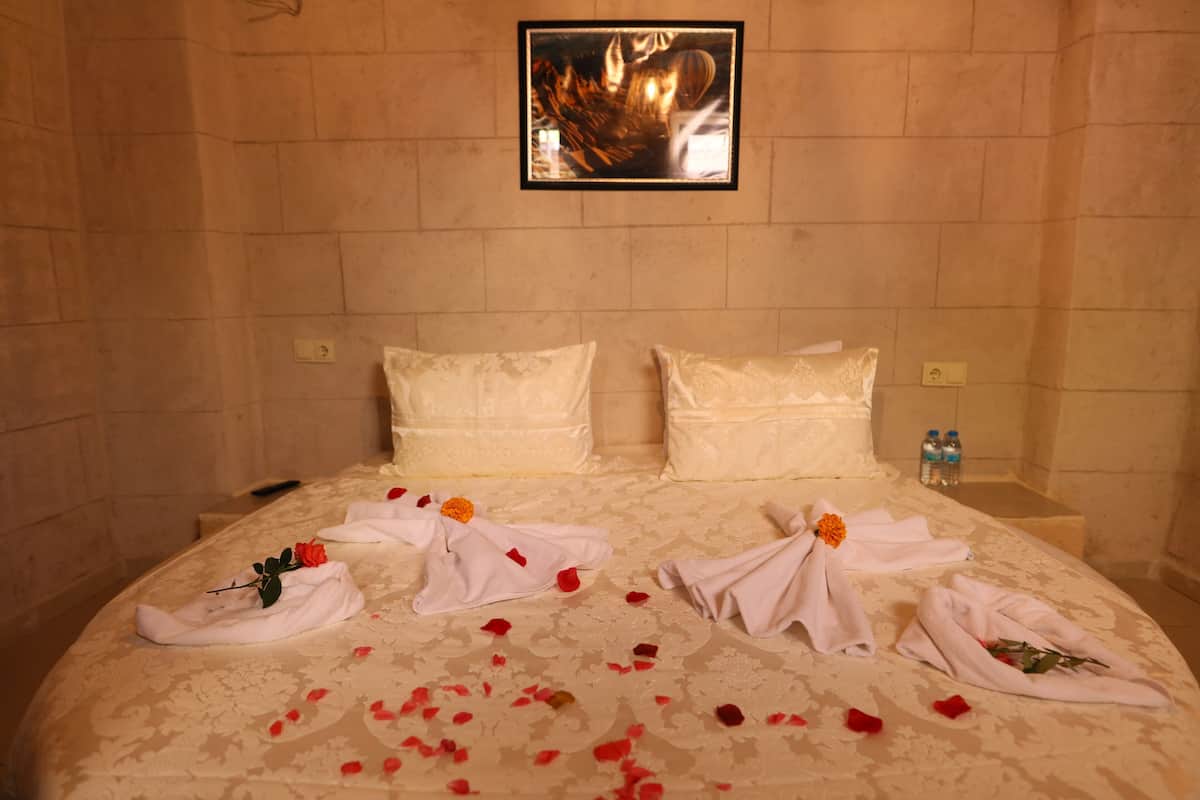 A hotel room with a bed, pillows, and a framed picture on the wall.