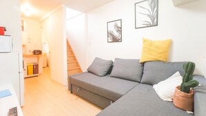 A modern living room with a grey sofa, a small cactus plant, and a yellow pillow.