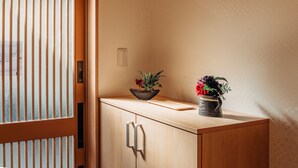 Ett träskåp med en skål med blommor och en svart mugg ovanpå.