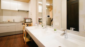 A modern kitchen with white cabinets, a double sink, and a microwave. - TSURUYA (Osaka)