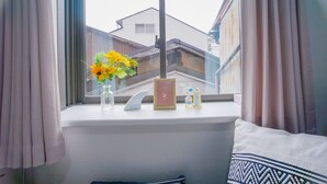 A window with a vase of flowers, a framed picture, and two bottles on a ledge. - NICE HOUSE (Osaka)