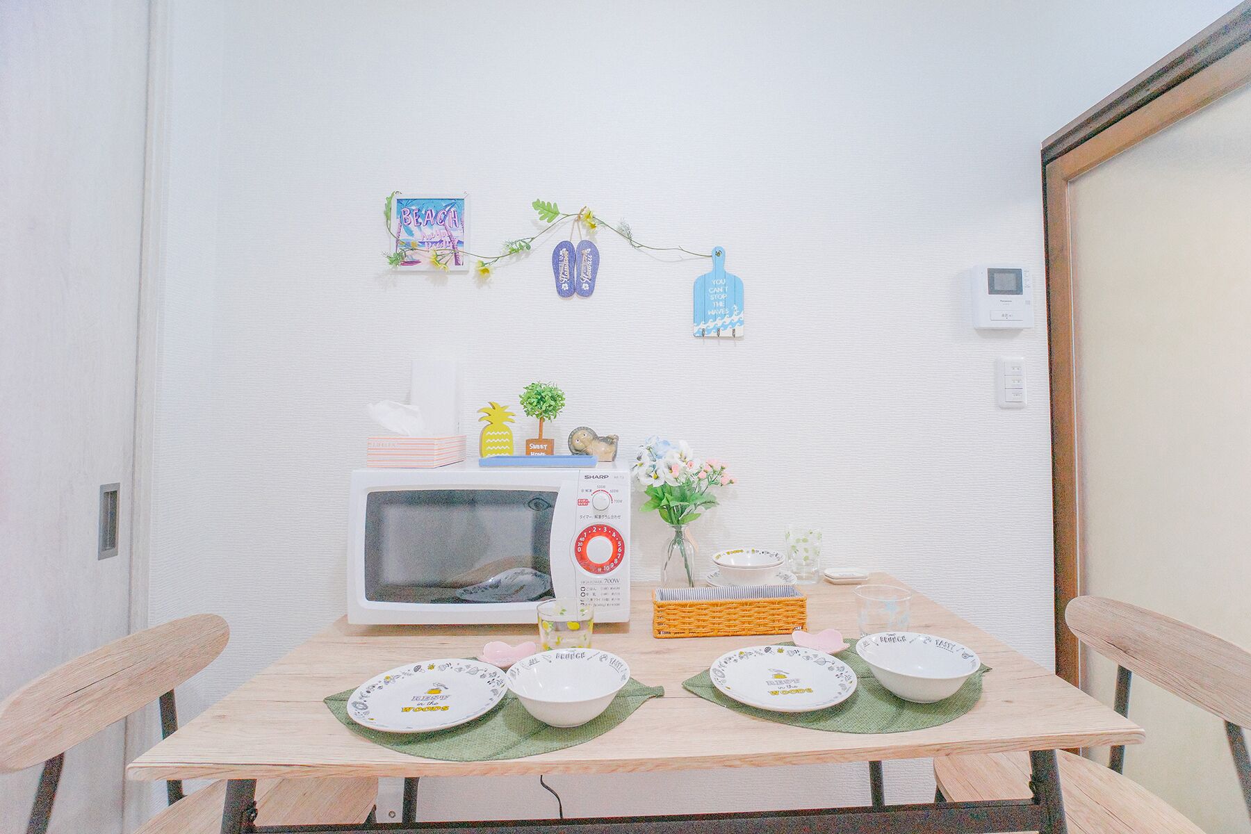 A small dining area with a microwave, a small table, and a few decorative items on the wall.