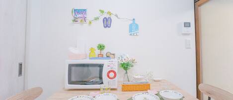 A small dining area with a microwave, a small table, and a few decorative items on the wall.
